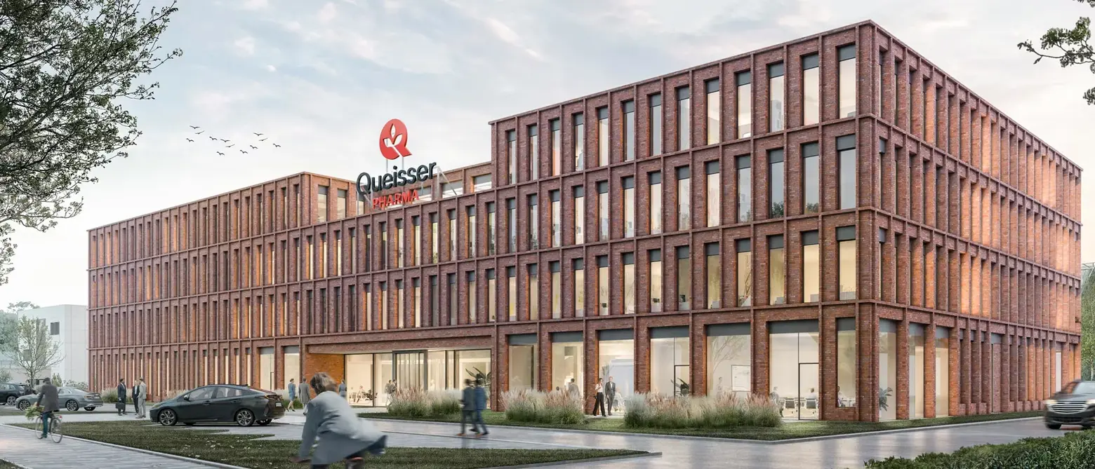 На изображении показано современное здание с фасадом из красного кирпича. В верхней части здания видно логотип компании "Quieser". Перед зданием находятся люди и автомобили, а на заднем фоне – небо с птицами.